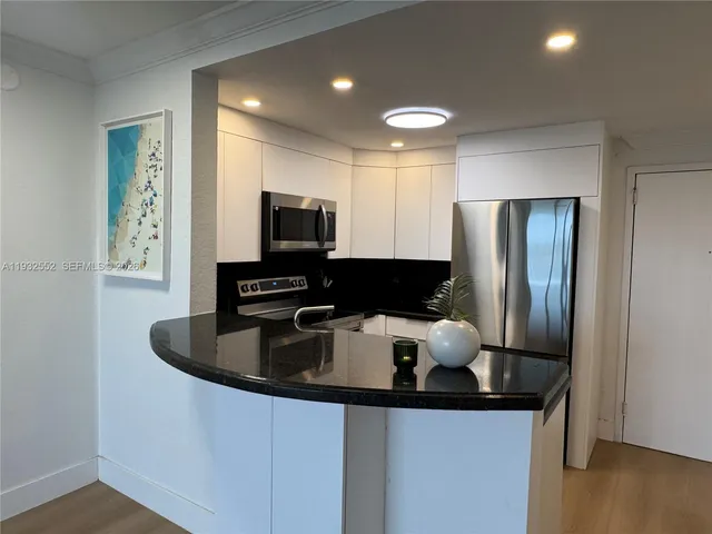 a kitchen with stainless steel appliances granite countertop a sink and a refrigerator