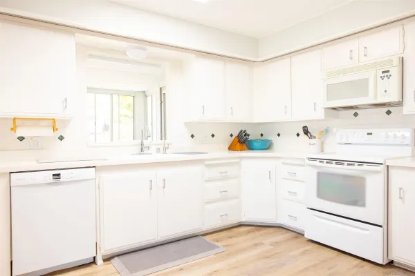 a kitchen with cabinets a sink and white appliances