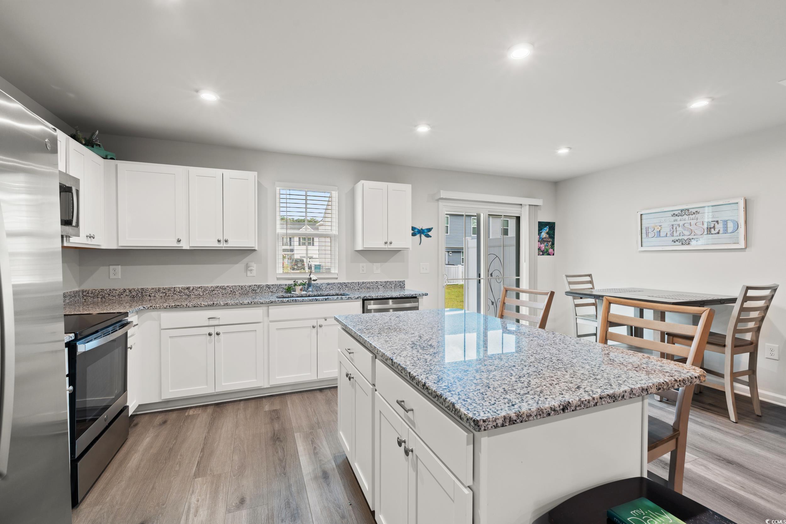 301 Granada Street, Unit D Myrtle Beach, SC 29579 - Photo 3 of 33 Kitchen with a breakfast bar, light stone counters, stainless steel appliances, a center island, and white cabinetry