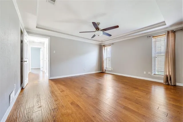 a view of empty room with wooden floor and fan