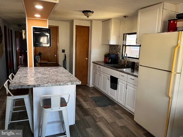 a kitchen with stainless steel appliances kitchen island granite countertop a refrigerator a stove and a sink