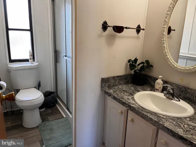 a bathroom with a granite countertop sink toilet and mirror