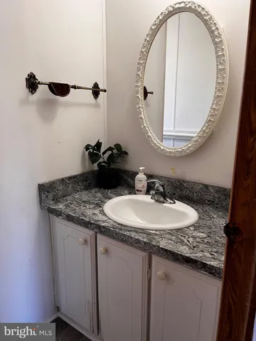 a bathroom with a granite countertop sink a mirror and shower