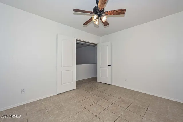 an empty room with a ceiling fan and a window