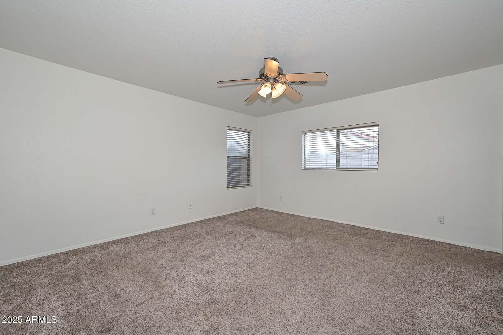 3038 West Roberta Drive Phoenix, AZ 85083 - Photo 18 of 40 an empty room with windows and chandelier fan