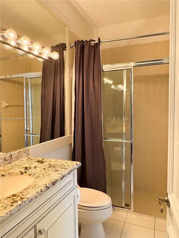 a bathroom with a granite countertop sink toilet and shower