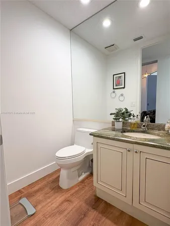a bathroom with a granite countertop toilet a sink and a mirror