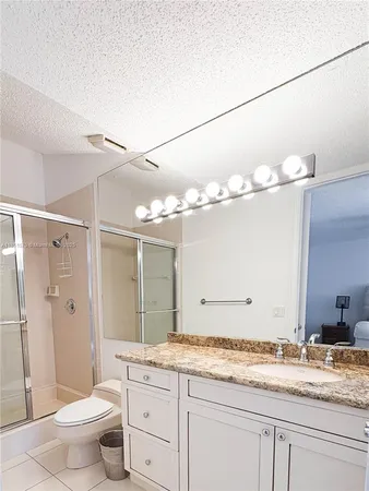 a bathroom with a granite countertop sink a toilet and a mirror
