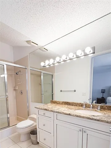 a bathroom with a granite countertop sink a toilet and a mirror