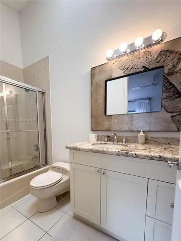 a bathroom with a granite countertop toilet sink mirror and shower