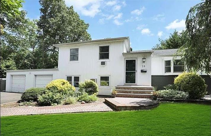 a front view of a house with a yard and green space