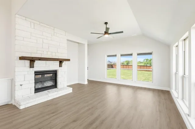 an empty room with wooden floor fireplace and windows