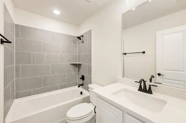 a bathroom with a bathtub shower sink vanity mirror and toilet