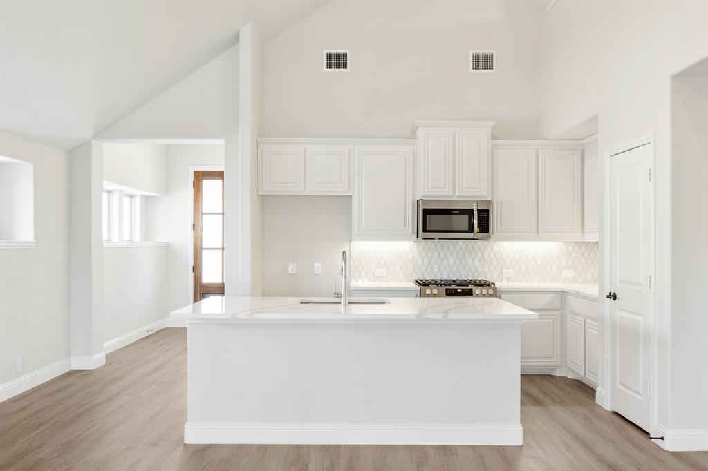 11916 Serval Street Godley, TX 76044 - Photo 7 of 35 a kitchen with kitchen island white cabinets appliances and sink