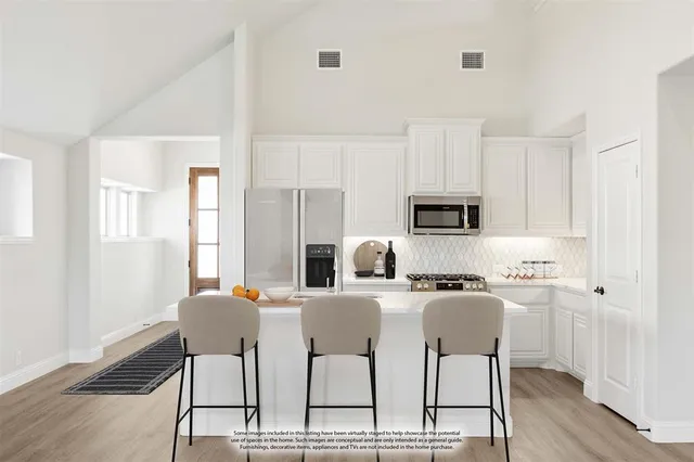 a kitchen with stainless steel appliances a dining table chairs microwave and sink