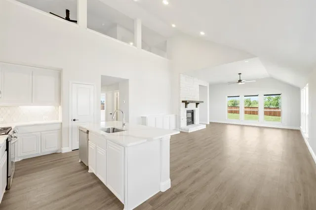 a large white kitchen with wide window and wooden floor
