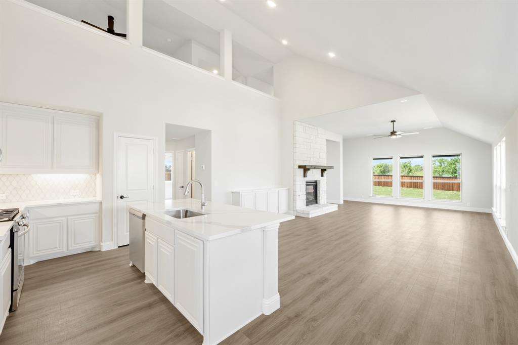 11916 Serval Street Godley, TX 76044 - Photo 9 of 35 a large white kitchen with wide window and wooden floor