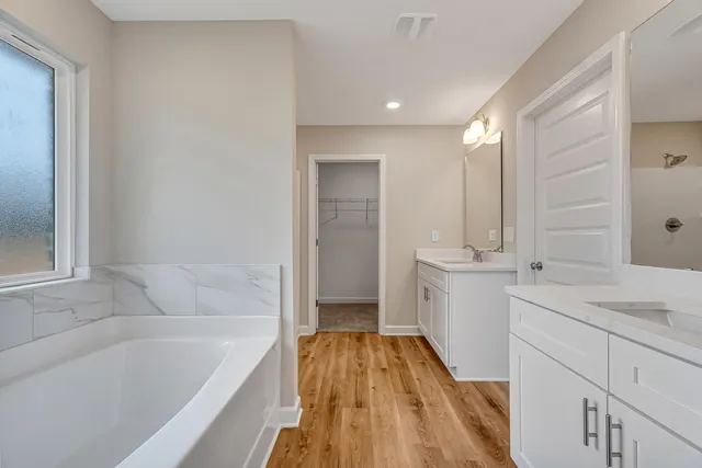 a spacious bathroom with a granite countertop sink mirror and a bathtub