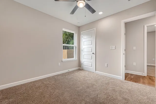 an empty room with windows and fan