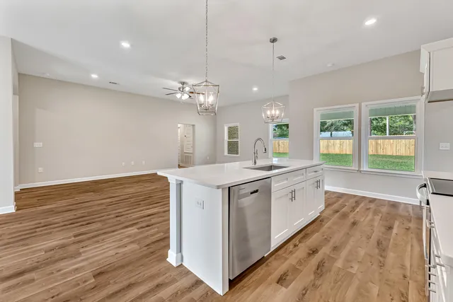 a large white kitchen with a large window a sink and stainless steel appliances