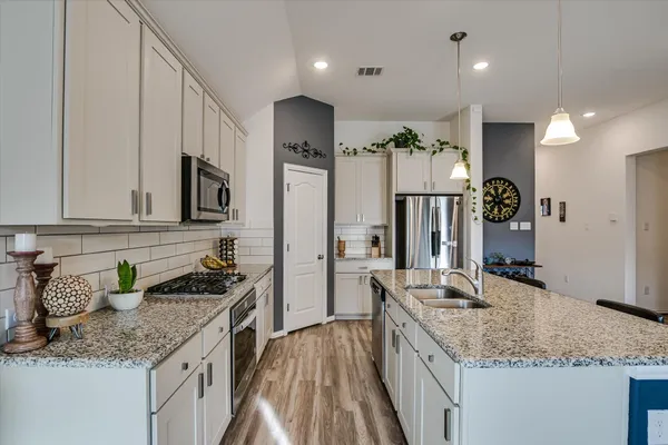 a kitchen with stainless steel appliances granite countertop a sink a stove and a refrigerator