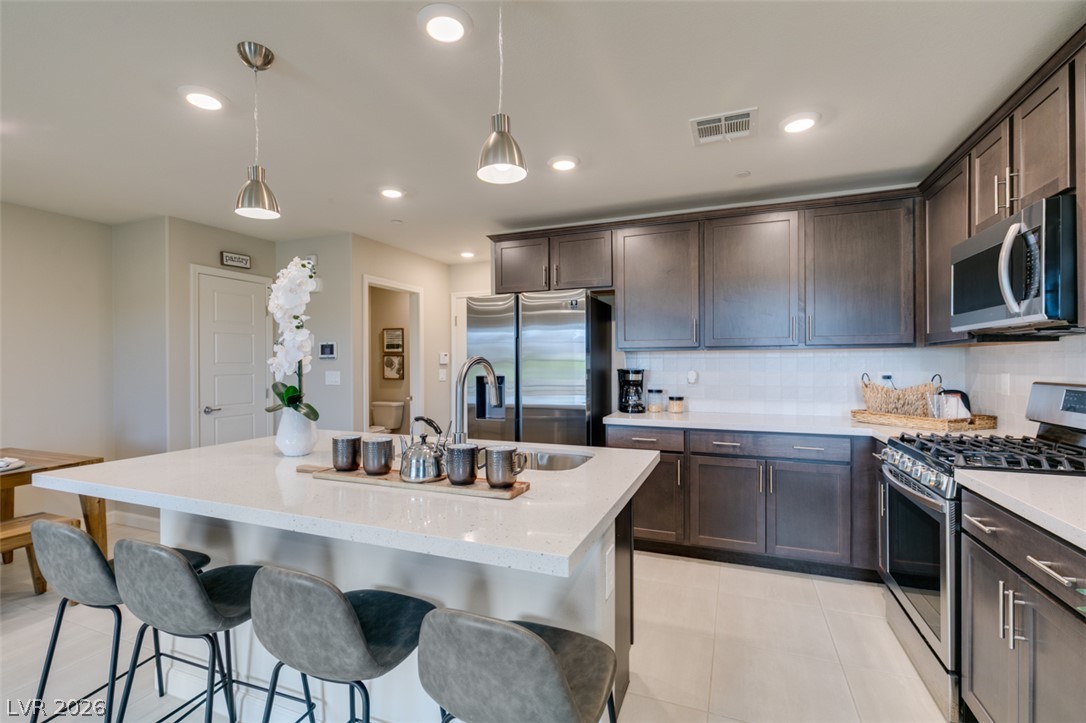 653 Pickled Pepper Place Henderson, NV 89011 - Photo 13 of 35 A well-lit kitchen with sleek cabinetry, a spacious island, and modern stainless steel appliances.