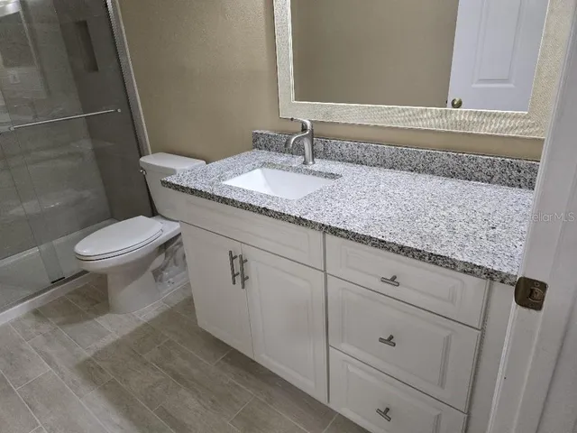 a bathroom with a granite countertop toilet sink and mirror