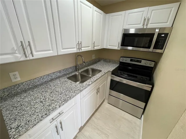 a kitchen with granite countertop a sink and a stove