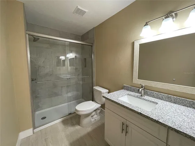 a bathroom with a granite countertop sink a toilet and shower