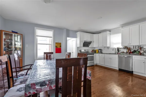 a kitchen with stainless steel appliances kitchen island granite countertop a refrigerator a stove a sink dishwasher and white cabinets with wooden floor