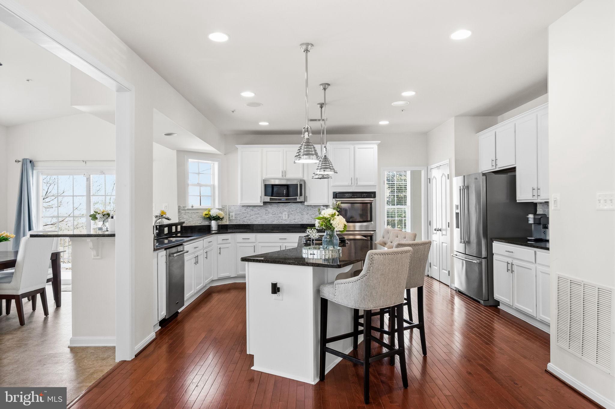11904 Parallel Road Bowie, MD 20720 - Photo 18 of 86 a kitchen with stainless steel appliances kitchen island granite countertop a dining table chairs refrigerator and sink
