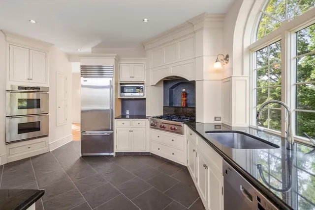 a kitchen with granite countertop a sink stainless steel appliances and cabinets