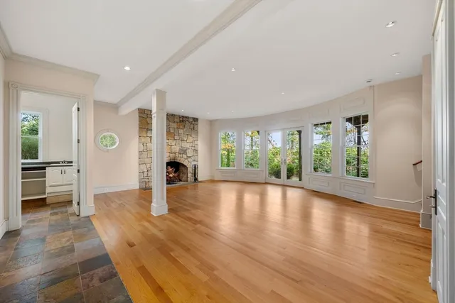 wooden floor in an empty room with a fireplace and a window