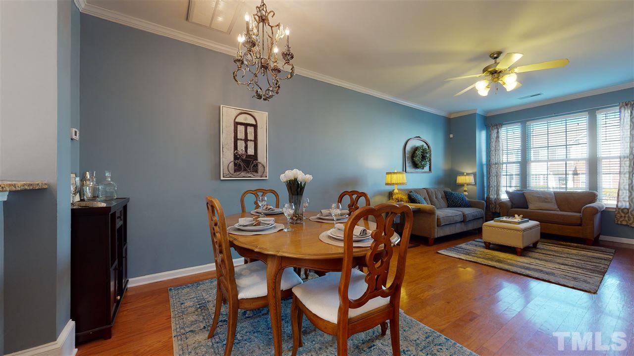 7621 Winners Edge Street Raleigh, NC 27617 - Photo 5 of 30 a living room with dining table and paintings on the wall with wooden floor