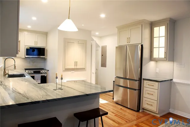 a kitchen with stainless steel appliances granite countertop a refrigerator a sink a stove a microwave a dining table and chairs with wooden floor