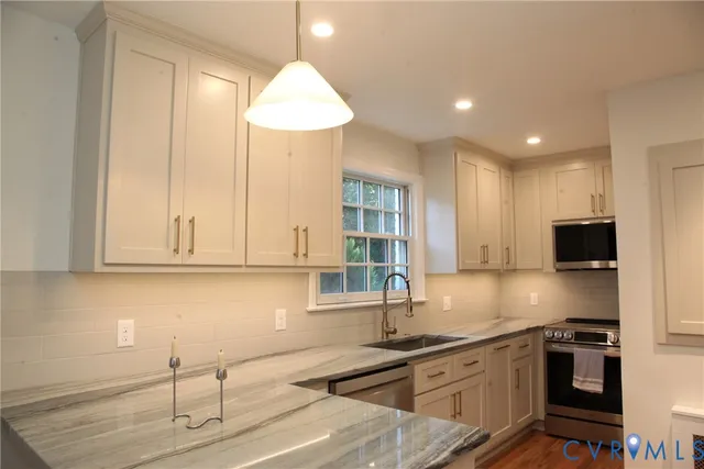 a kitchen with granite countertop a sink a stove and cabinets