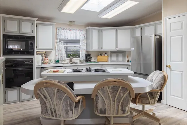 a living room with stainless steel appliances granite countertop furniture a fireplace a flat screen tv and a window