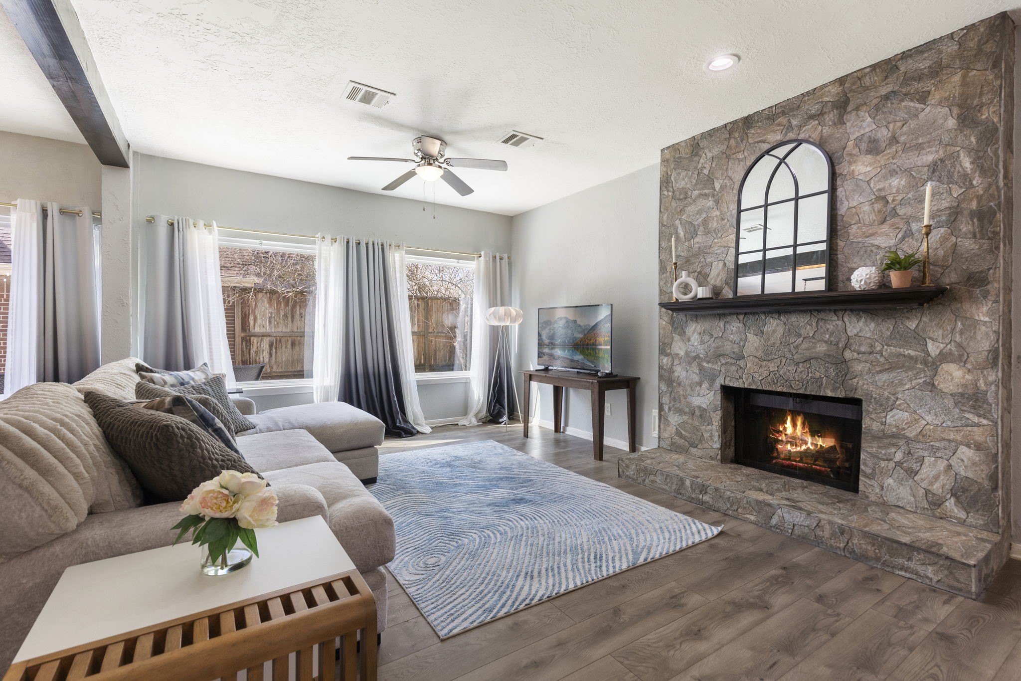 2110 Paso Rello Drive Houston, TX 77077 - Photo 9 of 41 This inviting living room features a cozy stone fireplace and large windows. The space is accented with a modern ceiling fan and very welcoming atmosphere.