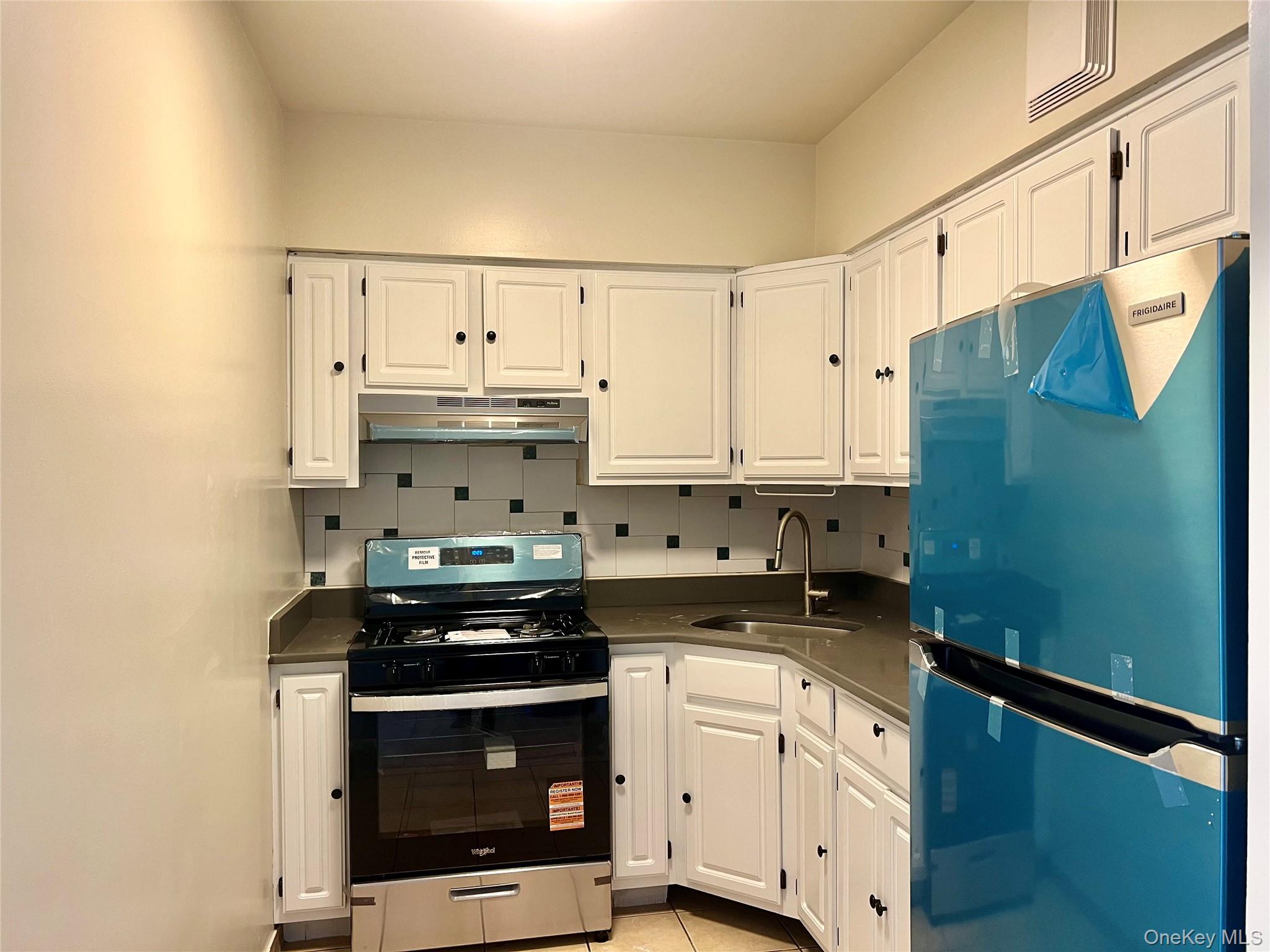 104-04 47th Avenue, Unit 2C Queens, NY 11368 - Photo 2 of 9 a kitchen with stainless steel appliances a stove a microwave and a refrigerator