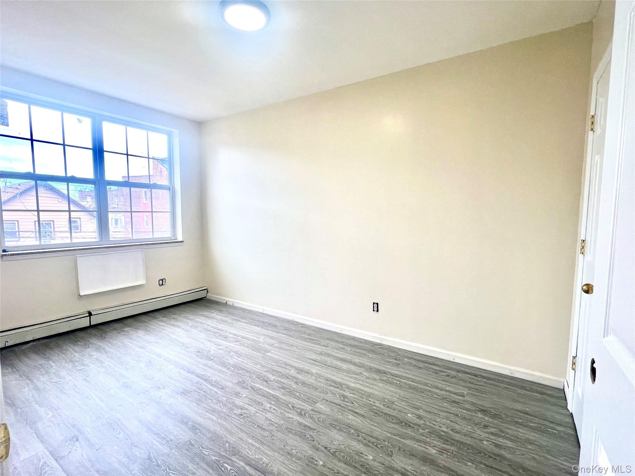 104-04 47th Avenue, Unit 2C Queens, NY 11368 - Photo 3 of 9 an empty room with wooden floor and windows