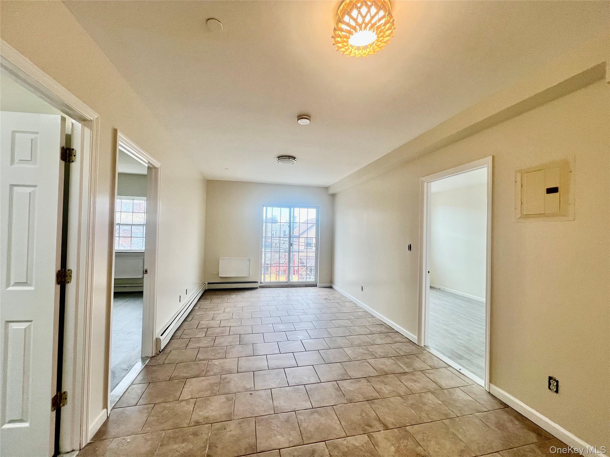 104-04 47th Avenue, Unit 2C Queens, NY 11368 - Photo 5 of 9 a view of a hallway with a chandelier fan and windows