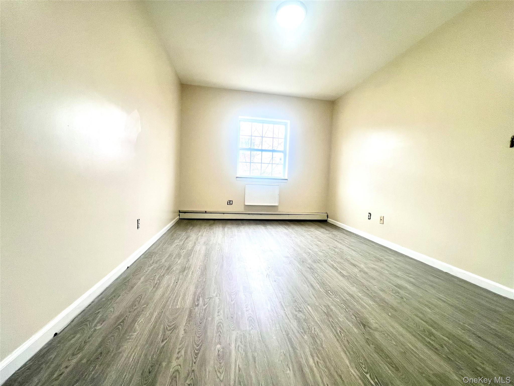 104-04 47th Avenue, Unit 2C Queens, NY 11368 - Photo 8 of 9 an empty room with wooden floor and windows