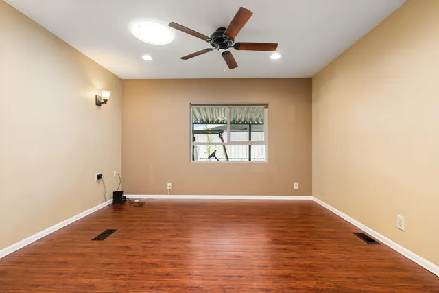 a view of empty room with wooden floor and fan