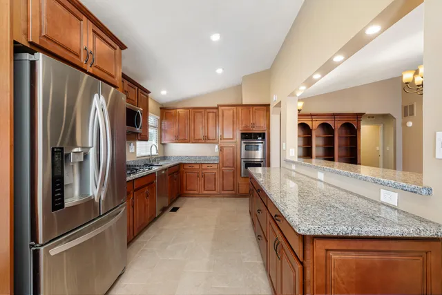 a large kitchen with stainless steel appliances granite countertop a refrigerator and a sink