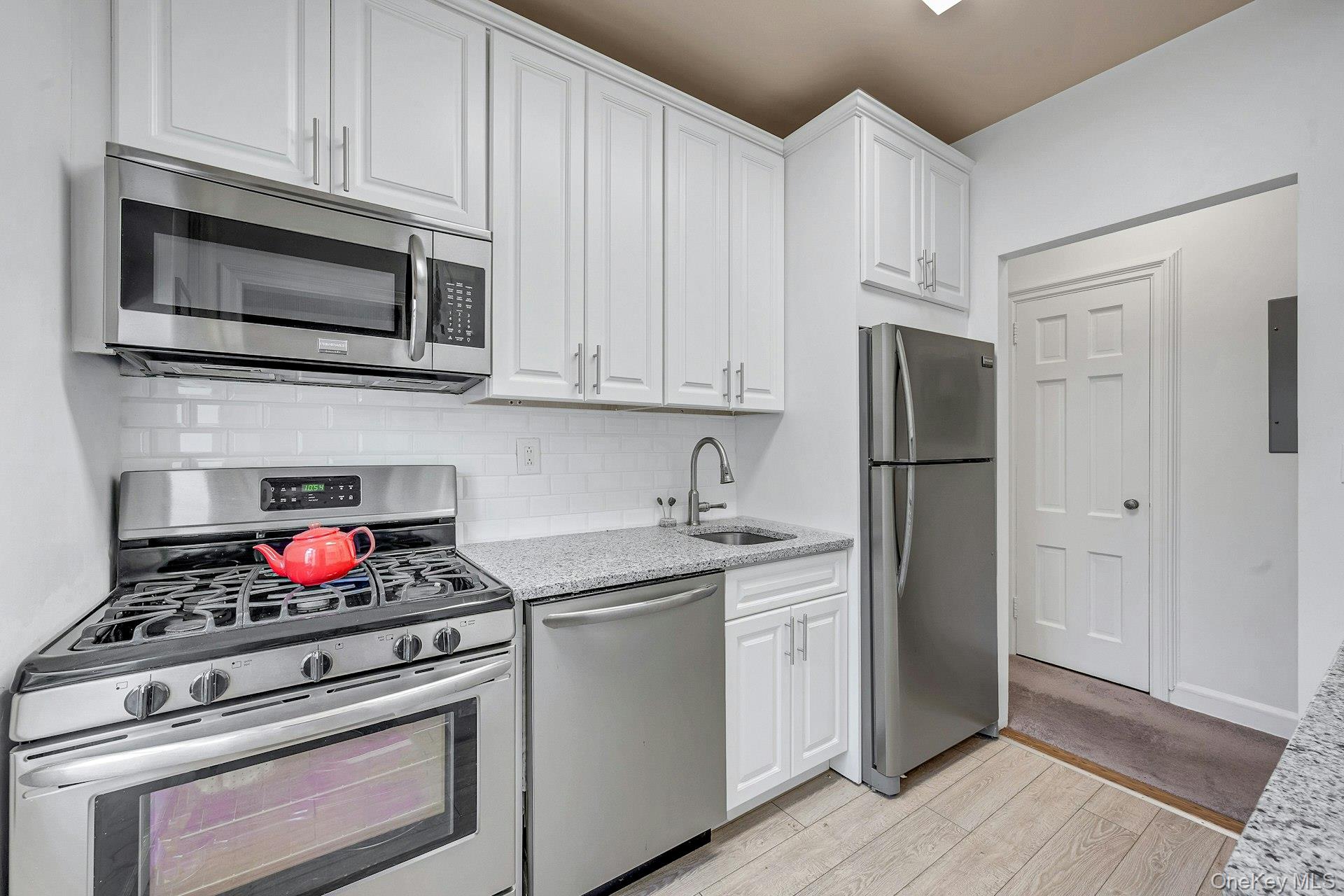 3 Midland Gardens, Unit 3H Bronxville, NY 10708 - Photo 12 of 20 a kitchen with stainless steel appliances granite countertop a stove microwave and refrigerator
