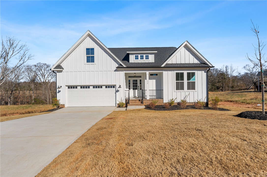 This newly constructed home features a crisp white facade, inviting entry, and an attached garage.