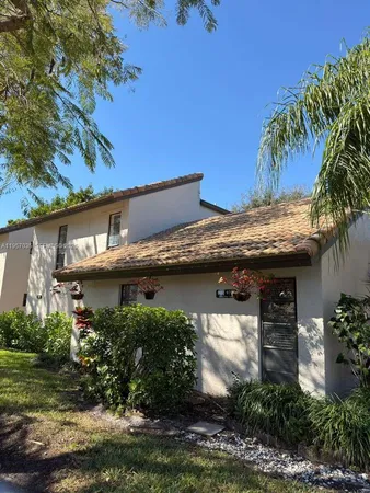 a view of a house with plants and large tree