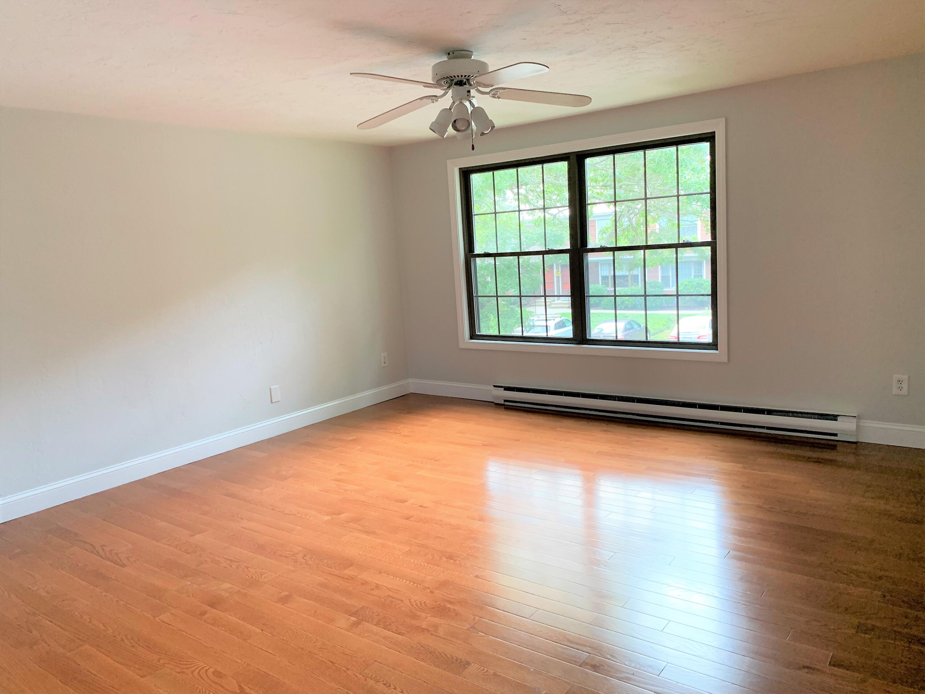 195 Falmouth Road, Unit 19D Mashpee, MA 02649 - Photo 11 of 17 an empty room with wooden floor and windows