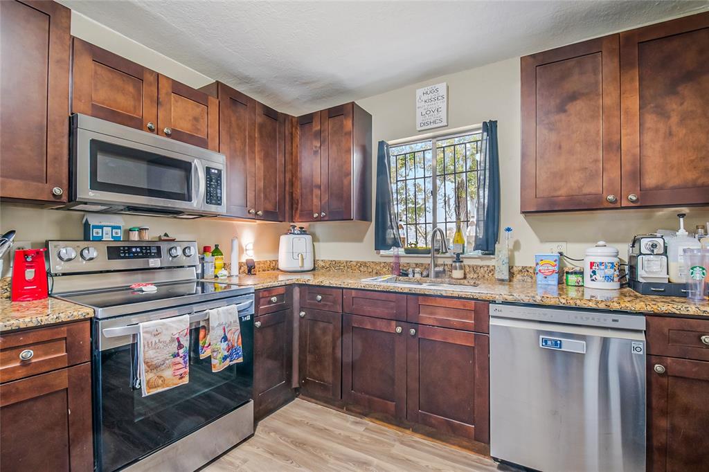 4432 Watch Hill Road Orlando, FL 32808 - Photo 15 of 30 a kitchen with stainless steel appliances granite countertop a stove sink microwave and cabinets