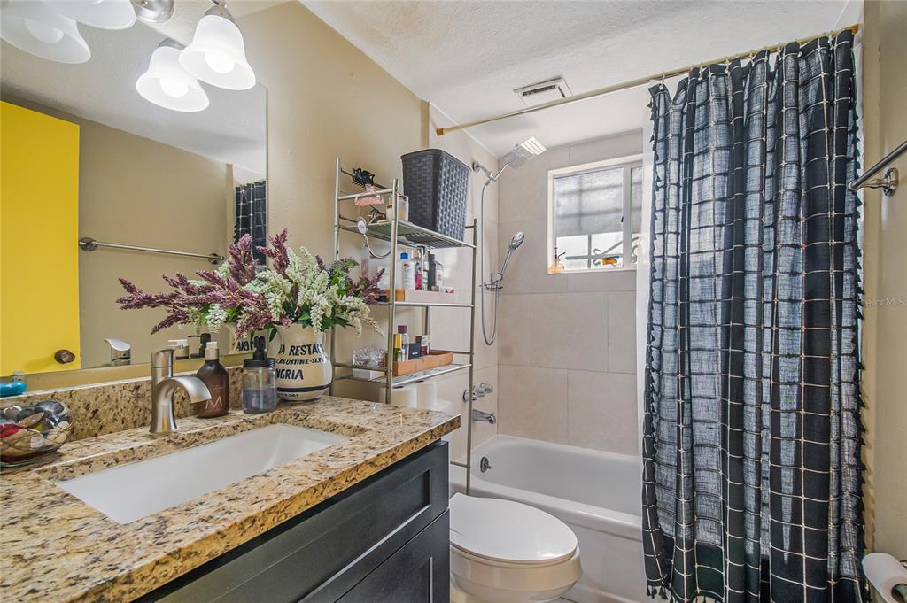 4432 Watch Hill Road Orlando, FL 32808 - Photo 21 of 30 a bathroom with a granite countertop sink a toilet and shower